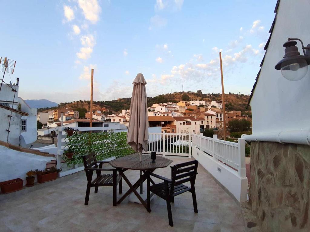 balcón con mesa, sillas y sombrilla en One bedroom house with private pool garden and wifi at Riogordo en Ríogordo