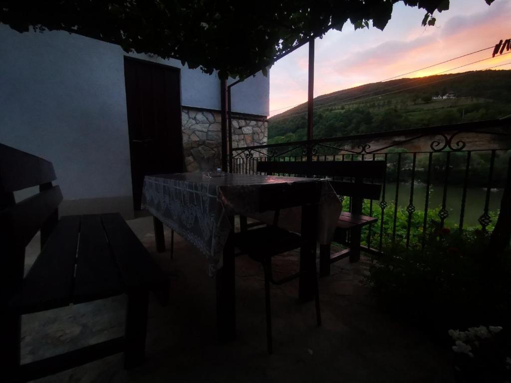 a table and chairs on a balcony with a sunset at Vikendica pored Drine Foča in Handići