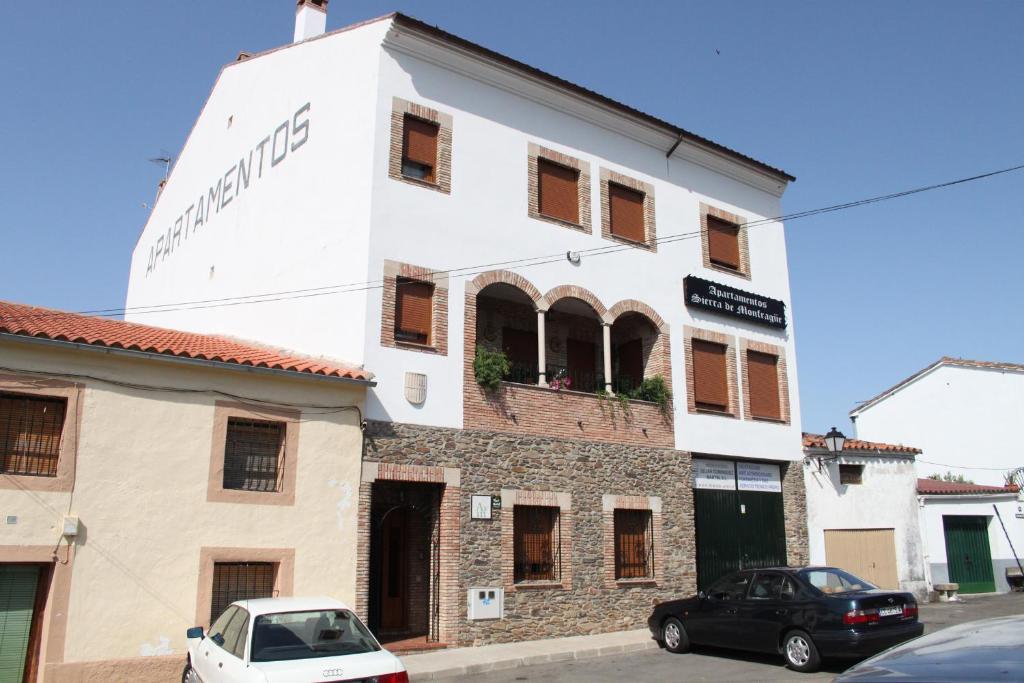un bâtiment blanc avec des voitures garées devant lui dans l'établissement Sierra De Monfrague, à Torrejón el Rubio