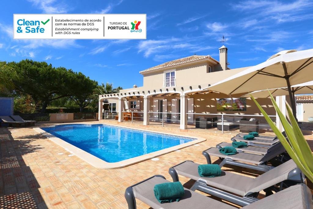 uma piscina com espreguiçadeiras e um guarda-sol em Quinta do Pinheiro Manso - Holidays Villa - Marinha Beach em Carvoeiro