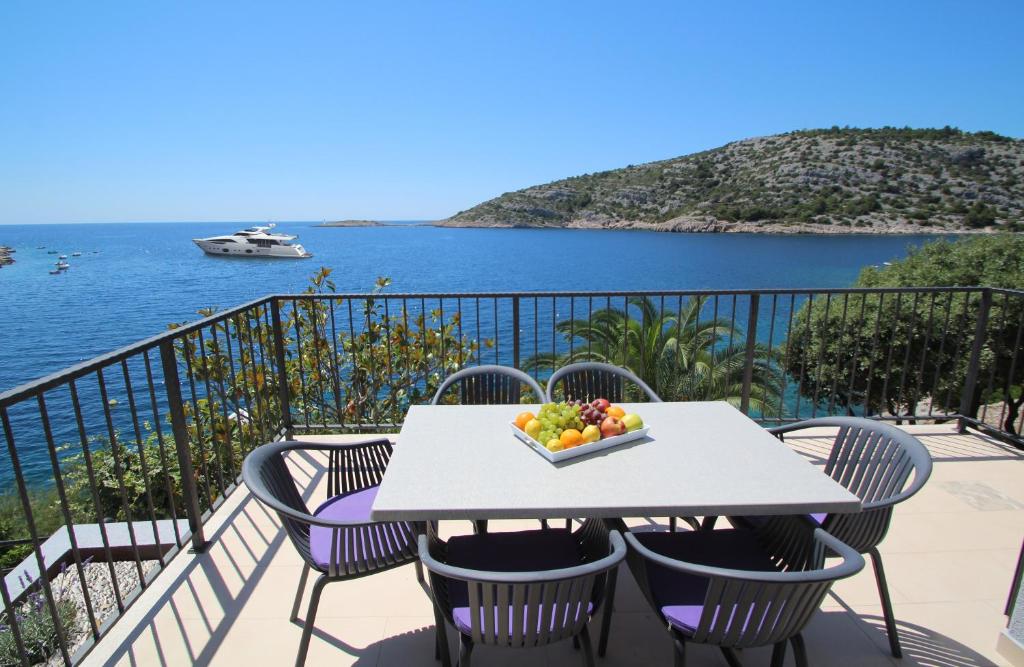 a table with a bowl of fruit on a balcony at Villa Lavanda Deluxe in Rogoznica