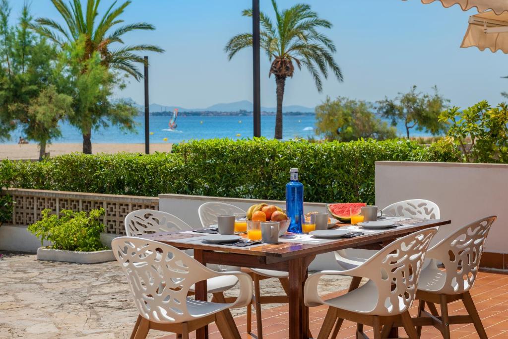 een houten tafel met stoelen op een patio met uitzicht op het strand bij Apartment La Bugambilia in Port de Pollença