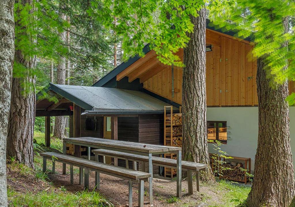 a cabin in the woods with benches in front of it at DAS HAUS IM WALD in Seefeld in Tirol