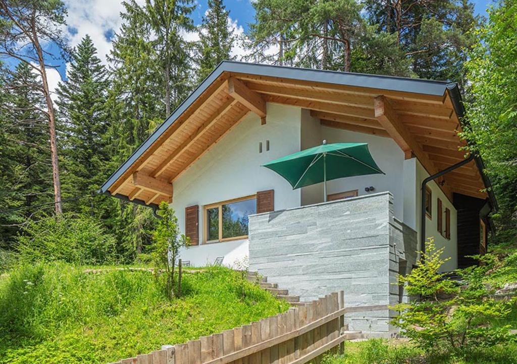 ein kleines Haus mit einem grünen Regenschirm darüber in der Unterkunft DAS HAUS IM WALD in Seefeld in Tirol