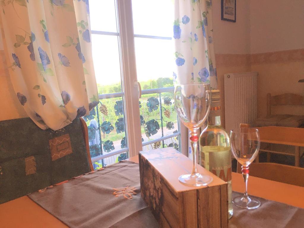 two wine glasses sitting on a table with a window at Ferienwohnung Südpfalzblick in Burrweiler