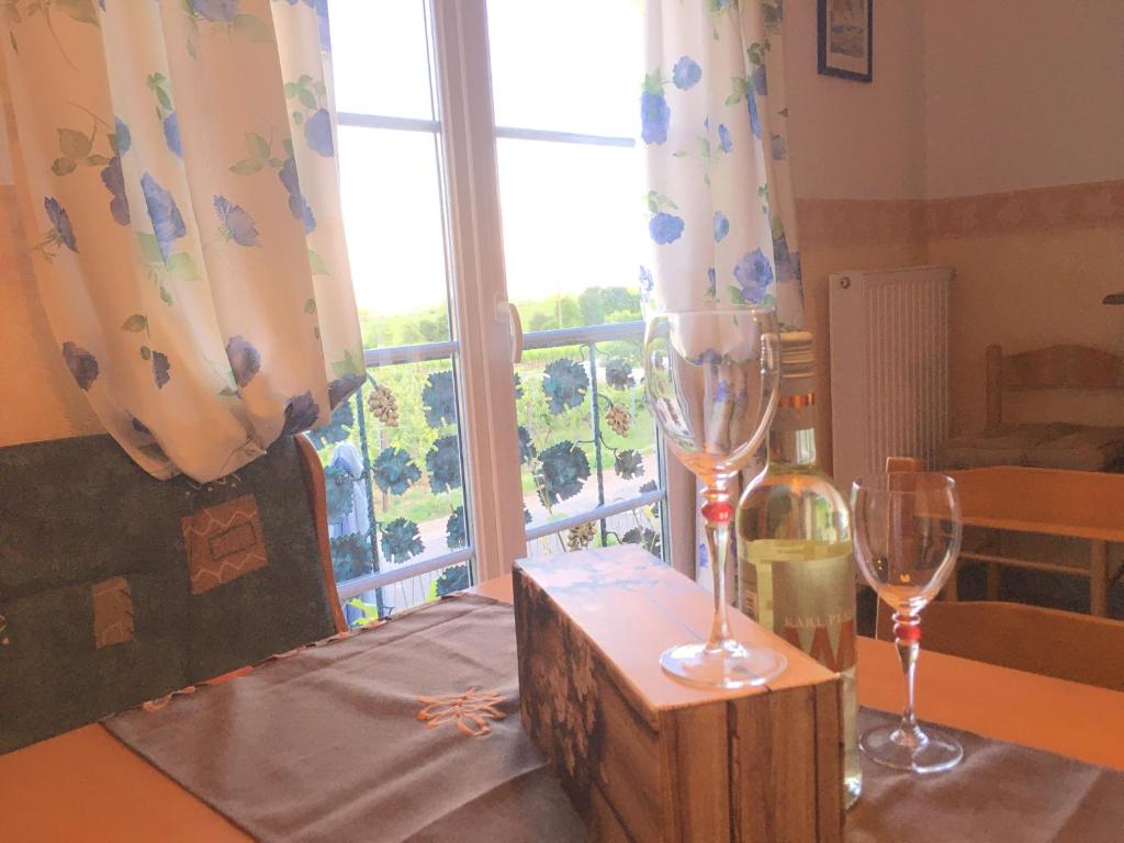 zwei Weingläser auf einem Tisch mit Fenster in der Unterkunft Ferienwohnung Südpfalzblick in Burrweiler