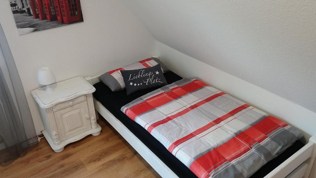 a small bed with a red and white striped blanket at Privates Zimmer bei der Weser-Ems-Halle in Oldenburg