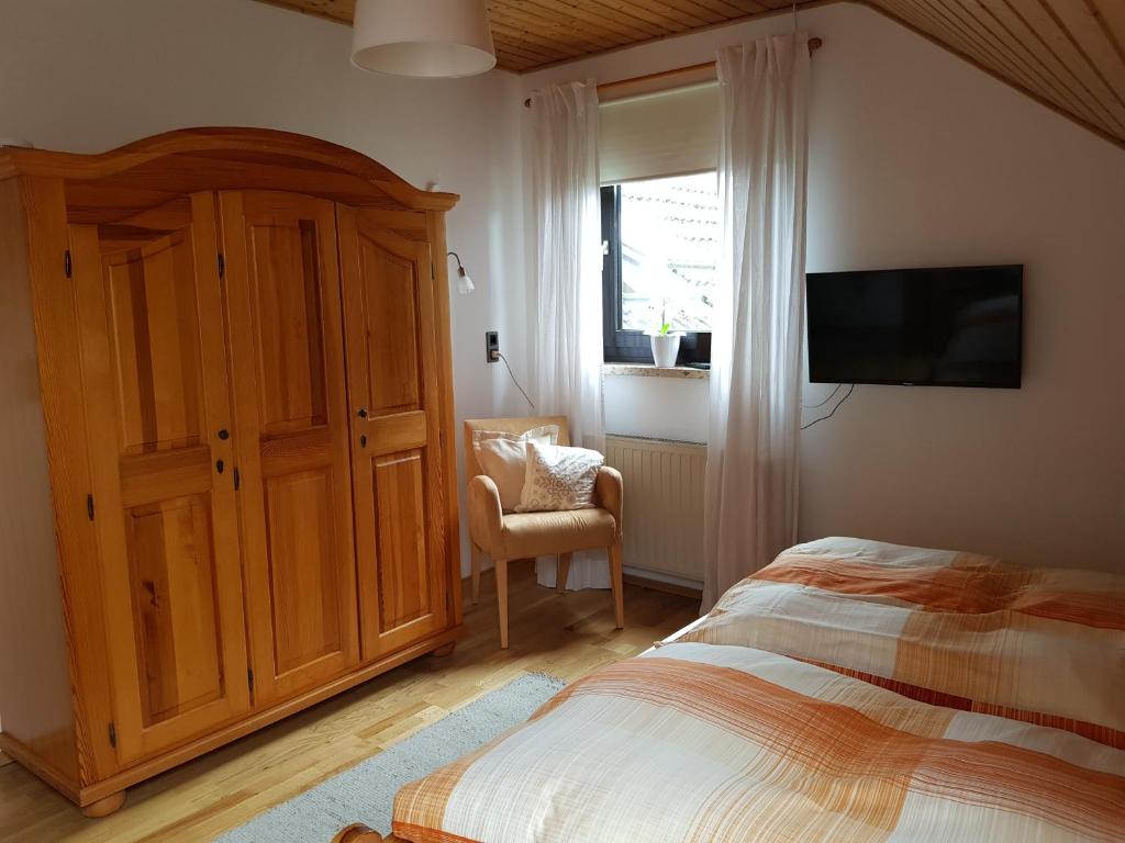 a bedroom with a bed and a television and a chair at Gästezimmer Aschenbrenner in Bad Rodach