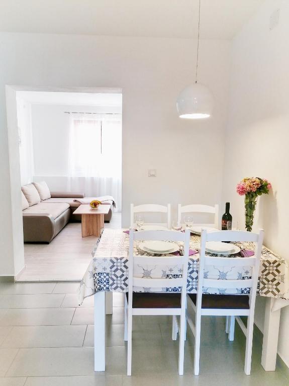 a white dining room with a table and chairs at Apartments Valiža 2 in Senj