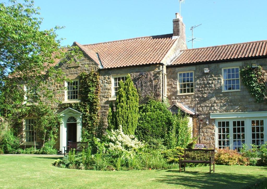 ein Steinhaus mit einer Bank im Hof in der Unterkunft Ox Pasture Hall Hotel in Scarborough