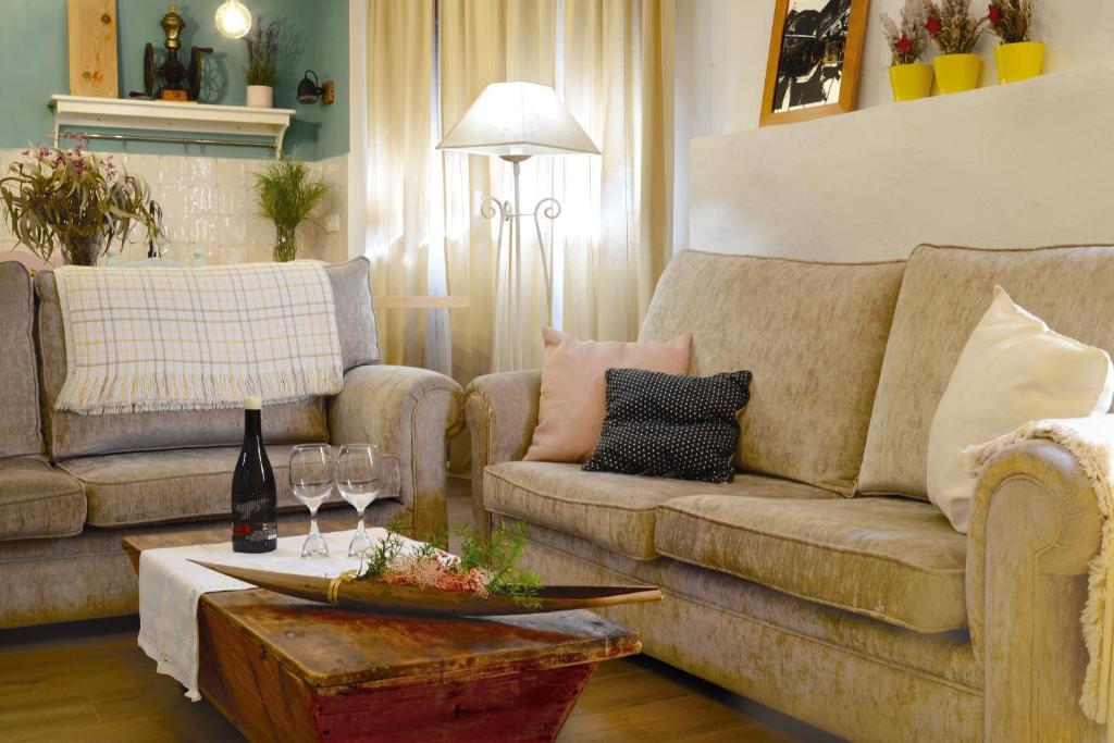 a living room with two couches and a table with wine glasses at PERIQUiNA CASA RURAL CON ENCANTO in Munébrega