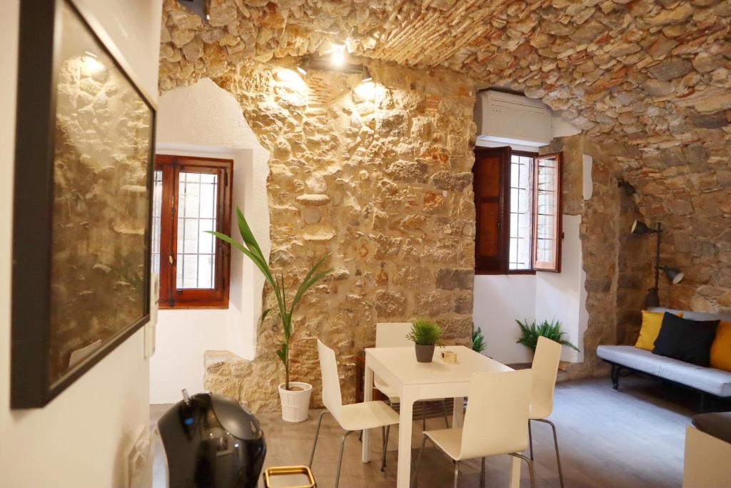 una sala da pranzo con parete in pietra, tavolo e sedie di Girona Catedral a Girona