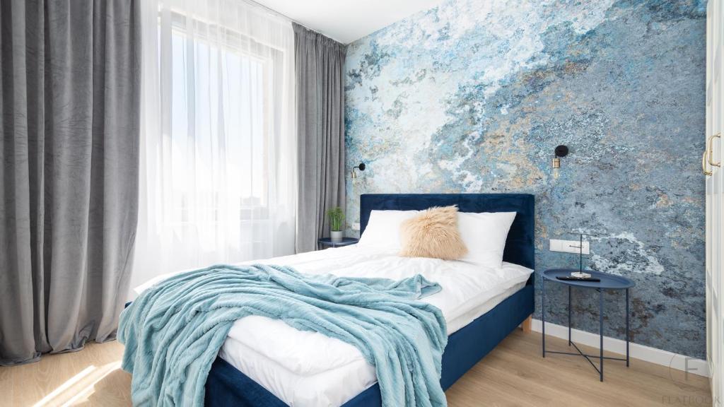 a bedroom with a bed with a blue wall at Flatbook - City Center Apartments in Gdańsk