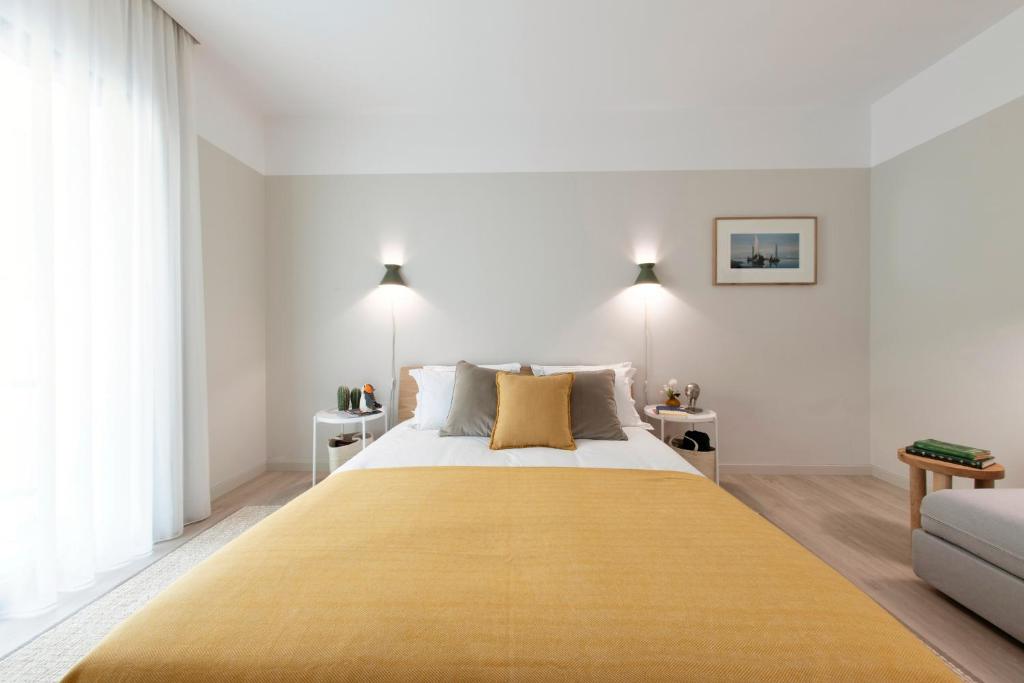 a bedroom with a large bed with a yellow blanket on it at Art Home Apartments in Aveiro