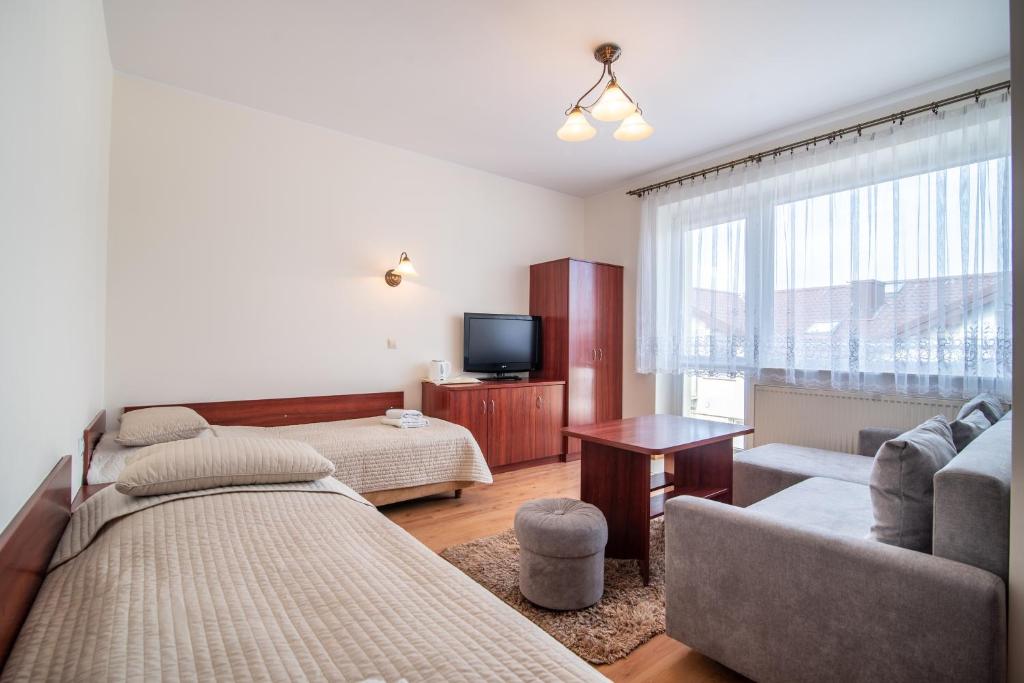 sala de estar con cama, sofá y TV en ALBATROS, en Władysławowo