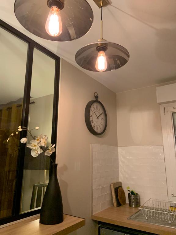 ein Badezimmer mit einer Uhr und einer Vase mit Blumen in der Unterkunft Luxury Appartement Disneyland in Magny-le-Hongre