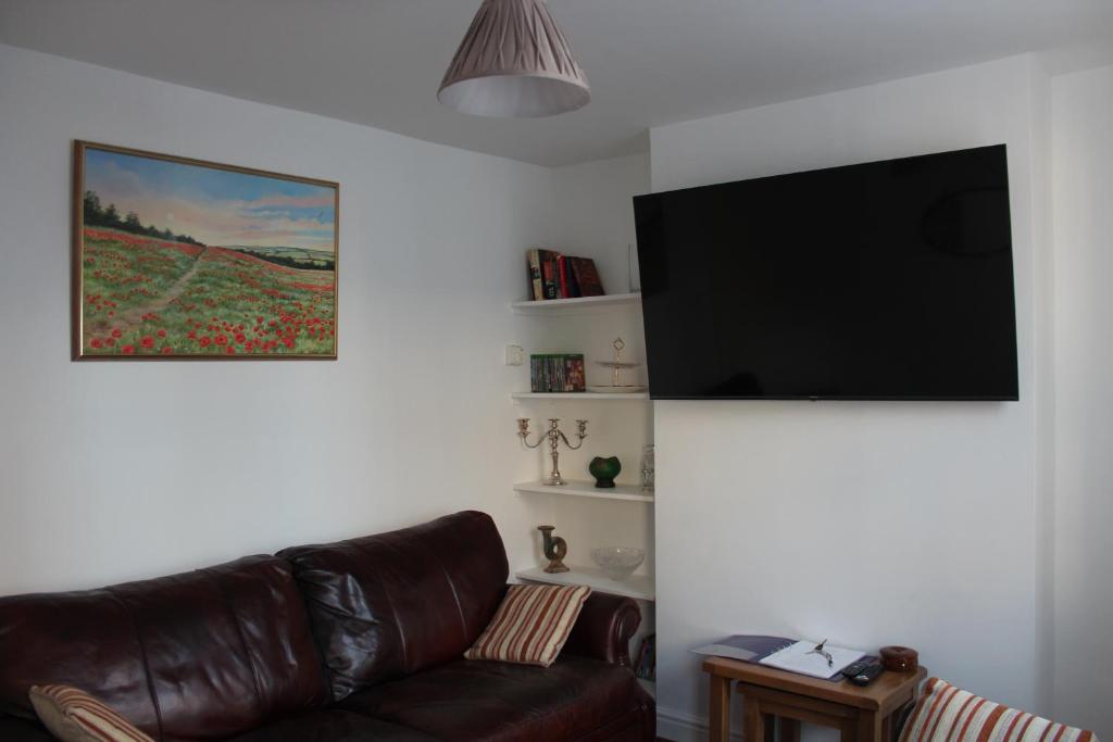 a living room with a couch and a flat screen tv at Deal Cottage 5 minutes walk to the beach & Town centre in Deal