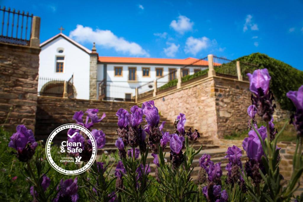 uma casa com flores roxas em frente em Convento Da Serta Hotel na Sert