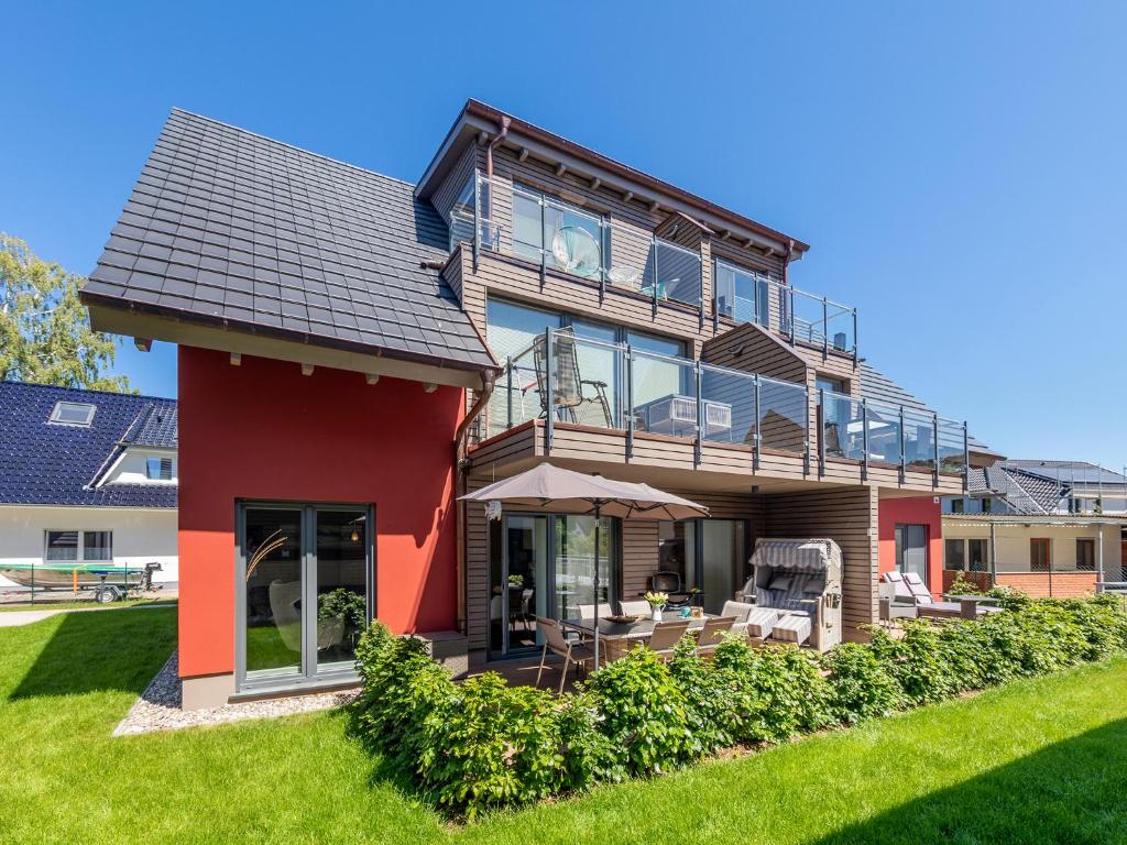 ein rotes Haus mit Balkon und Rasen in der Unterkunft Suite Windböe in Zingst