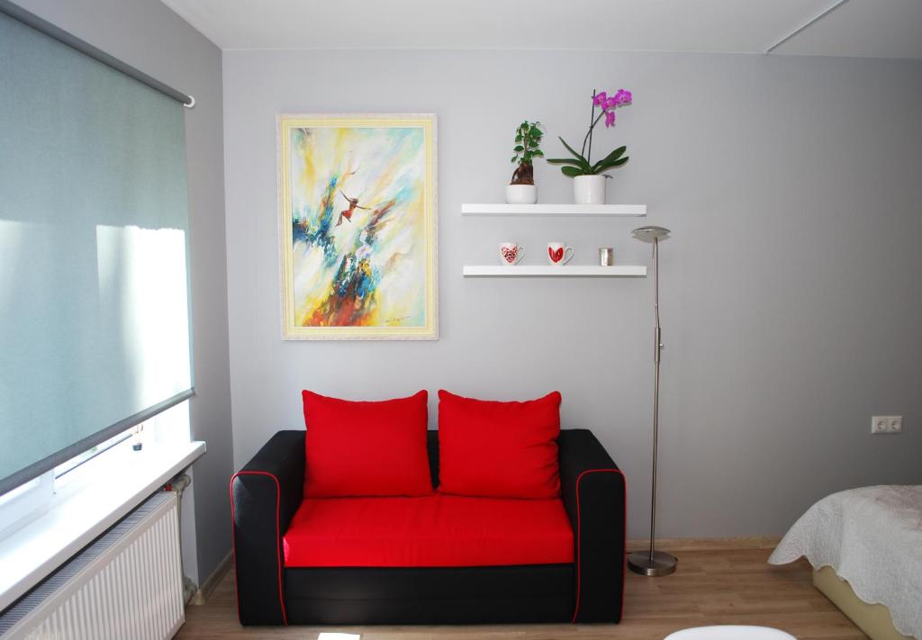 a red couch in a living room with a tv at Phoenix apartment in Jūrmala