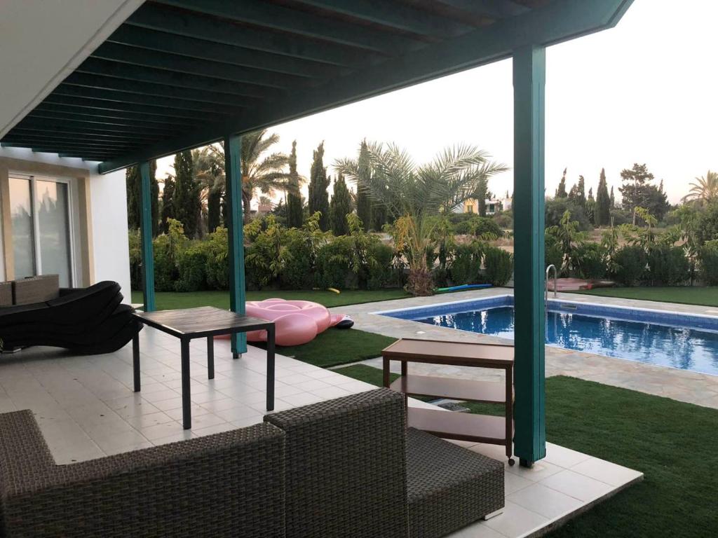 a covered patio with a table and chairs next to a swimming pool at Oasi Rejuve Poseidon in Meneou