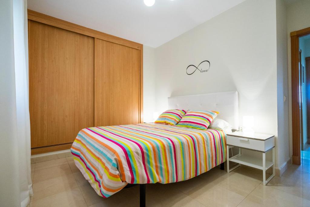 una camera da letto con un letto con una coperta colorata a righe di Playa Torrecilla Piscina Centro 2 Habitaciones a Nerja