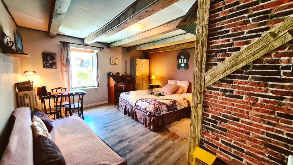 een slaapkamer met 2 bedden en een bakstenen muur bij Le Doux Nid in Chanaz