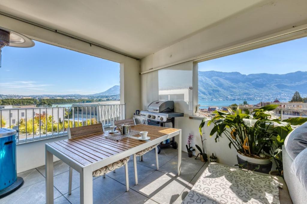 uma varanda com uma mesa e vistas para as montanhas em le panorama du lac em Annecy