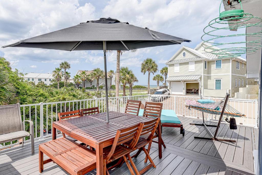 une table en bois avec un parasol sur une terrasse dans l'établissement Atlantic Shores Getaway steps from Jax Beach Private House Pet Friendly Near to the Mayo Clinic - UNF - TPC Sawgrass - Convention Center - Shopping Malls - Under 3 Hours from DISNEY, à Jacksonville Beach