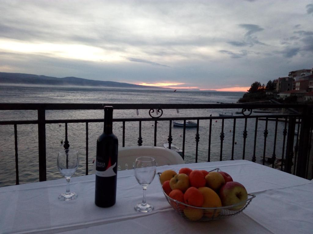 a bottle of wine and a bowl of fruit on a table at Apartment on the beach in Lokva Rogoznica
