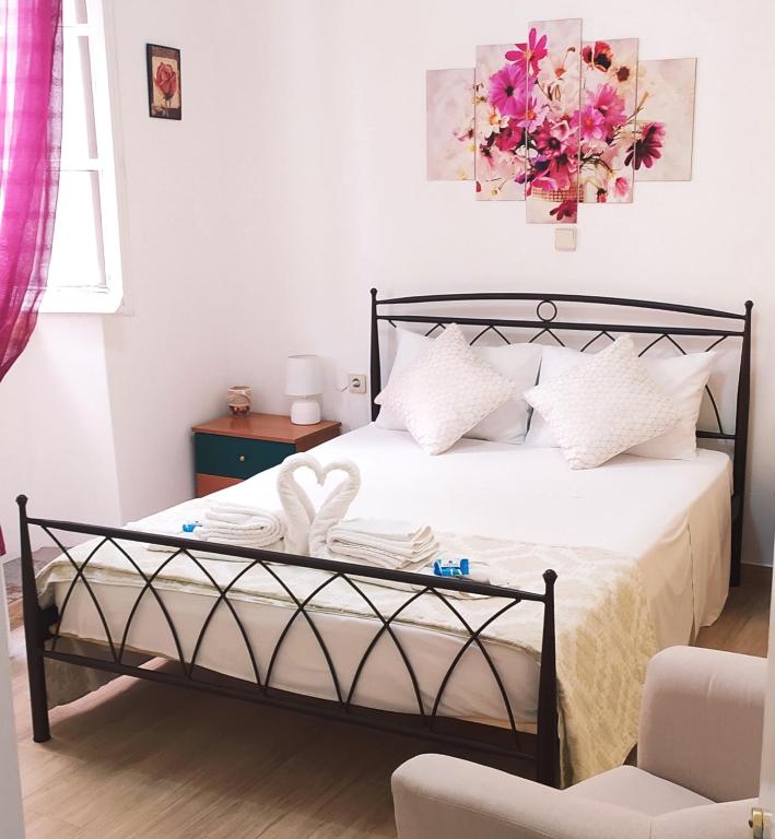 sypialnia z łóżkiem z białą pościelą i różowymi kwiatami w obiekcie Cofineta Apartment w Korfu