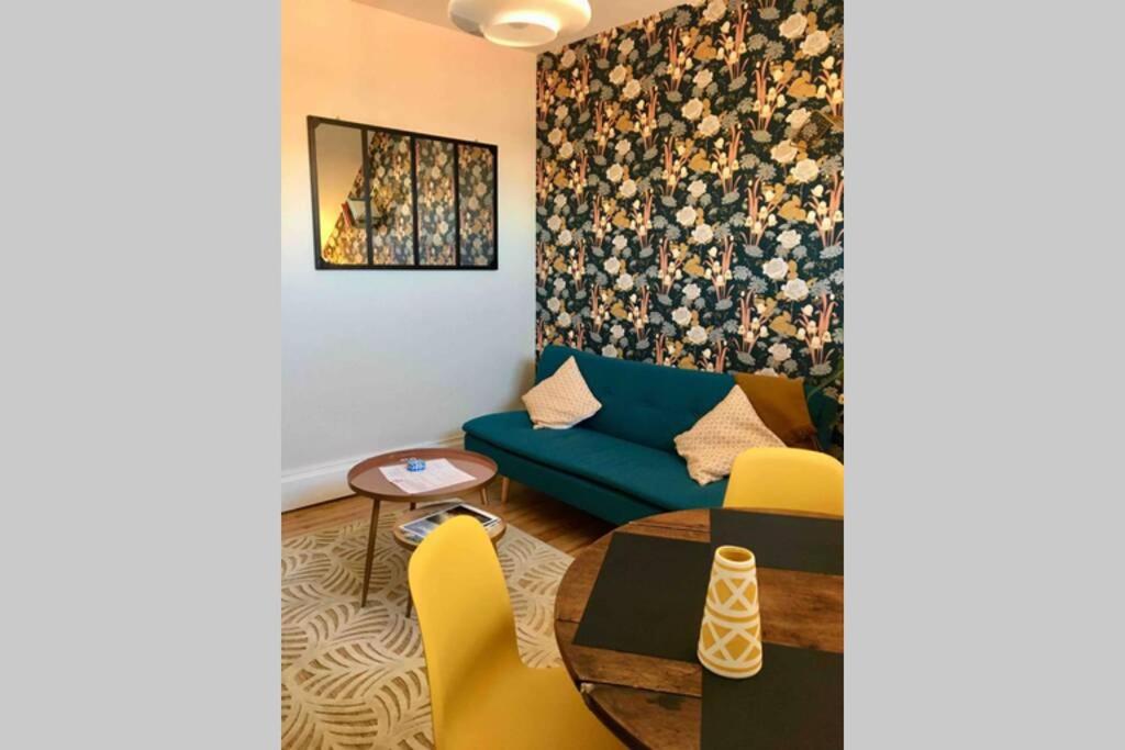 a living room with a blue couch and yellow chairs at Vichy Cocoon Appartements in Vichy