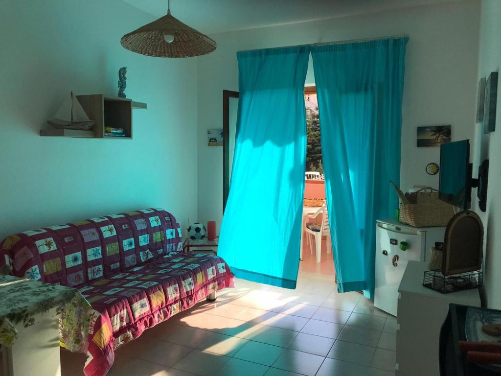 sypialnia z niebieskimi zasłonami i łóżkiem oraz tarasem w obiekcie CASA IL TRAMONTO w mieście San Nicola Arcella