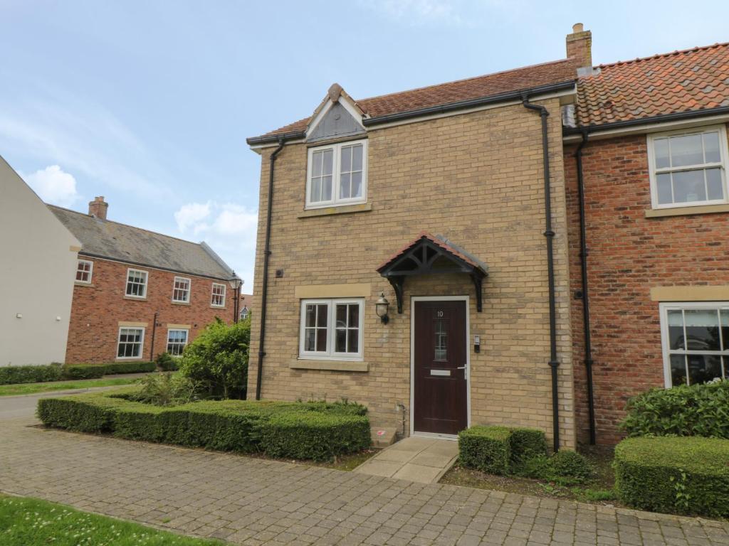 a brick house with a door and a driveway at Driftwood in Filey