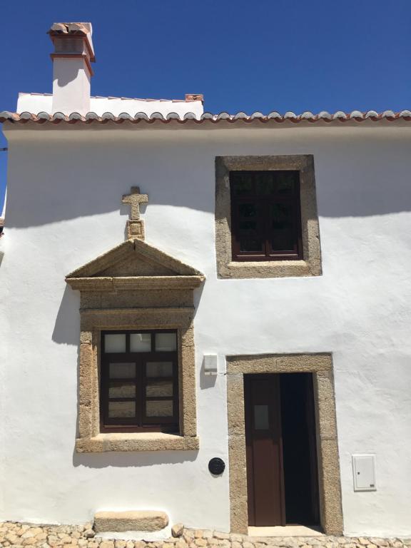 ein weißes Gebäude mit zwei Fenstern und einem Kreuz darauf in der Unterkunft Casa do Sétimo Passo in Marvão