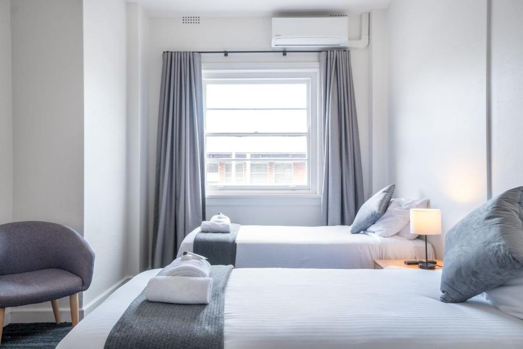 um quarto de hotel com duas camas e uma janela em Sydney Junction Hotel em Hamilton
