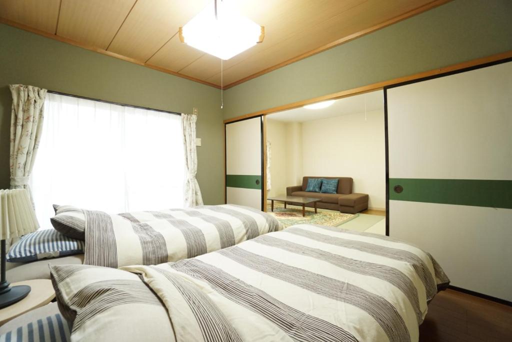 two beds in a room with a couch and a window at Mark's HOME in Maebashi