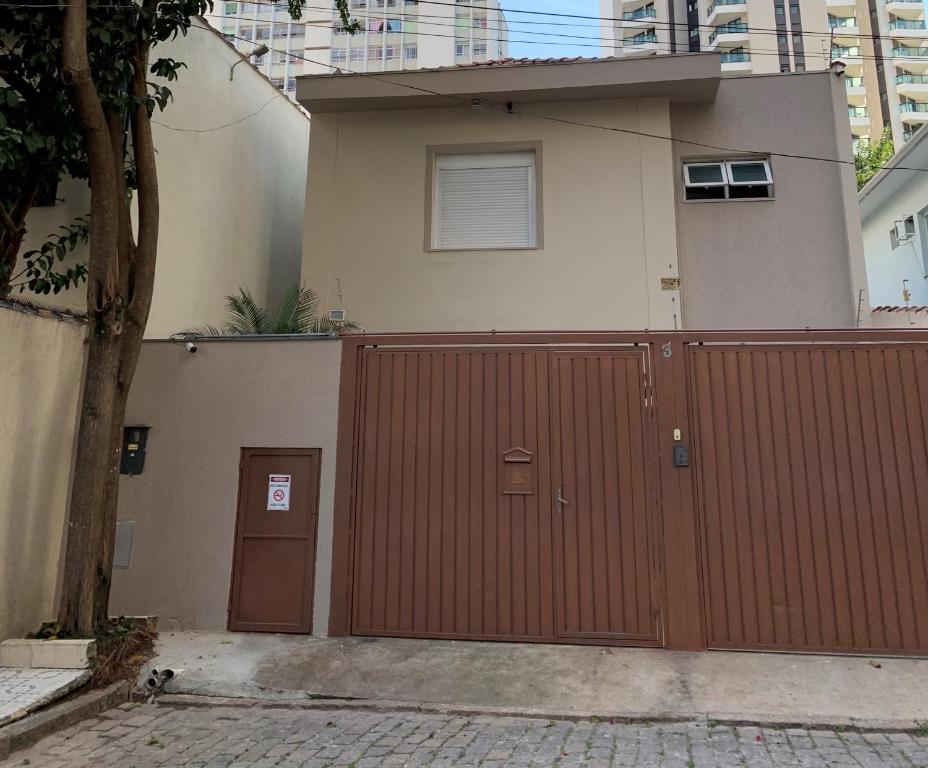 a house with a red fence and a building at Vila Stellino Suítes in Sao Paulo