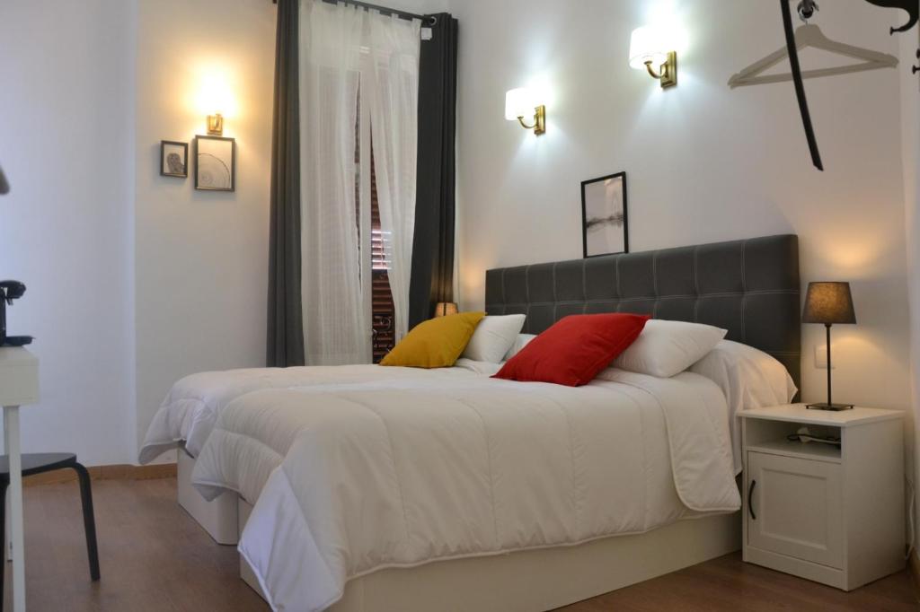 1 dormitorio con 2 camas con almohadas rojas y amarillas en Lux Penthouse gran vía, en Madrid