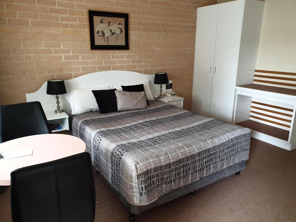 a bedroom with a bed and a brick wall at Blayney Central Motel in Blayney
