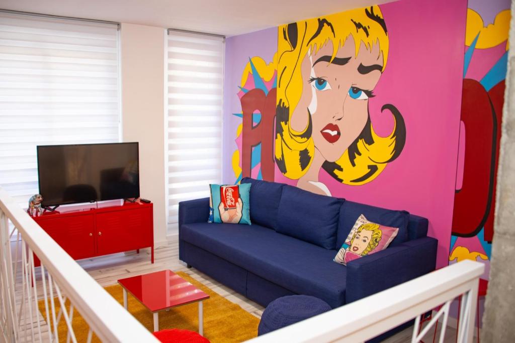 a living room with a blue couch and a colorful wall at Soraya's Place - Chopín 3 in Valencia