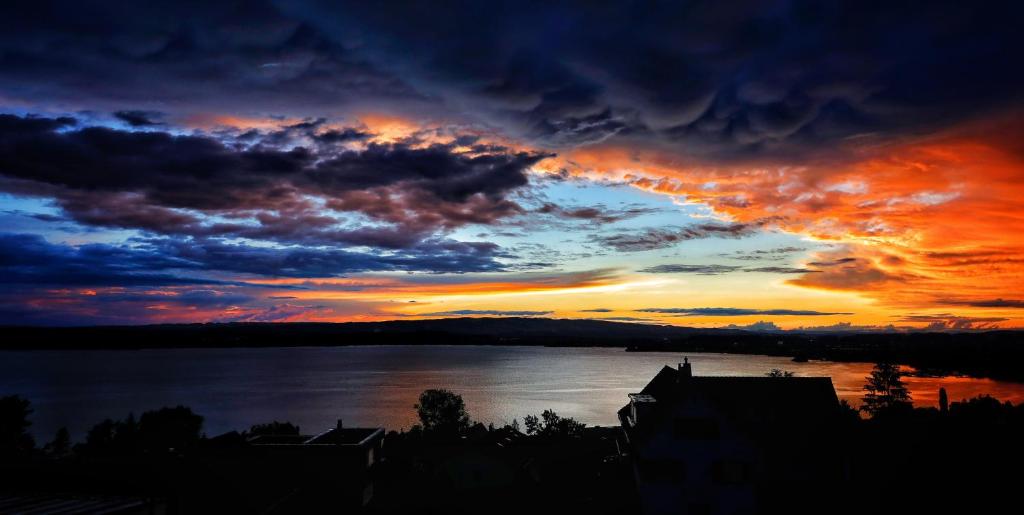 a sunset over a body of water with clouds at Guggital Hotel Restaurant in Zug