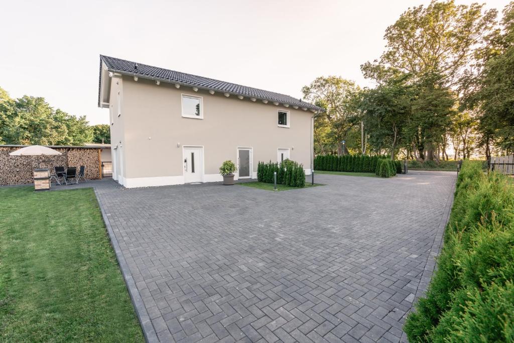 a white house with a brick driveway at Ostseehaus am Naturstrand - Ostseeblick in Varnkevitz