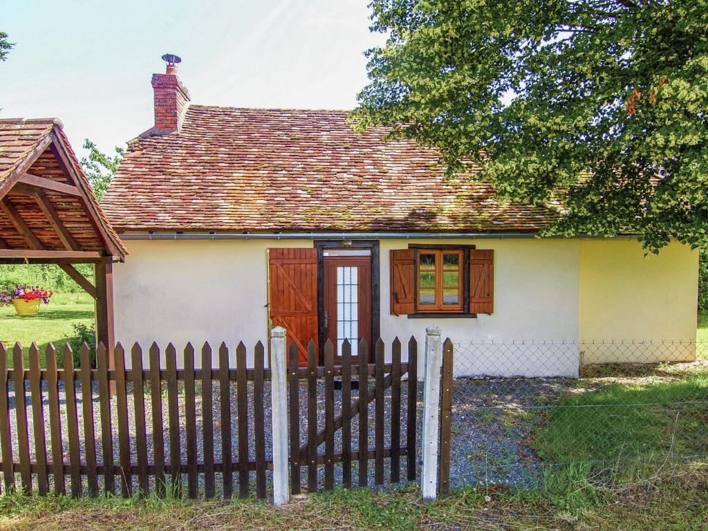 una piccola casa bianca con una recinzione in legno di Peaceful Cottage in Savignac a Savignac-Lédrier