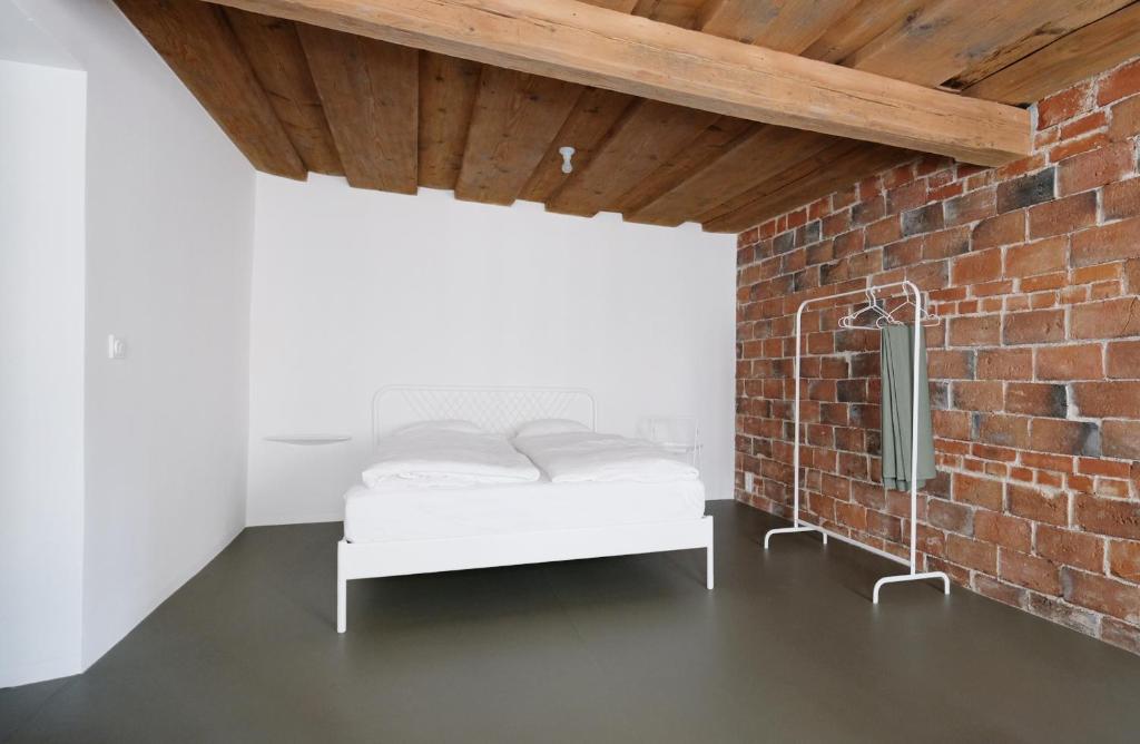 1 dormitorio con cama blanca y pared de ladrillo en ENTZÜCKENDE KLEINE WOHNUNG, en Linz