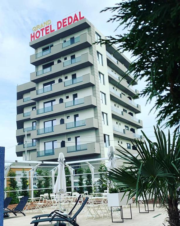 a hotel deal building with tables and chairs in front of it at Hotel Grand Dedal in Mamaia Sat/Năvodari