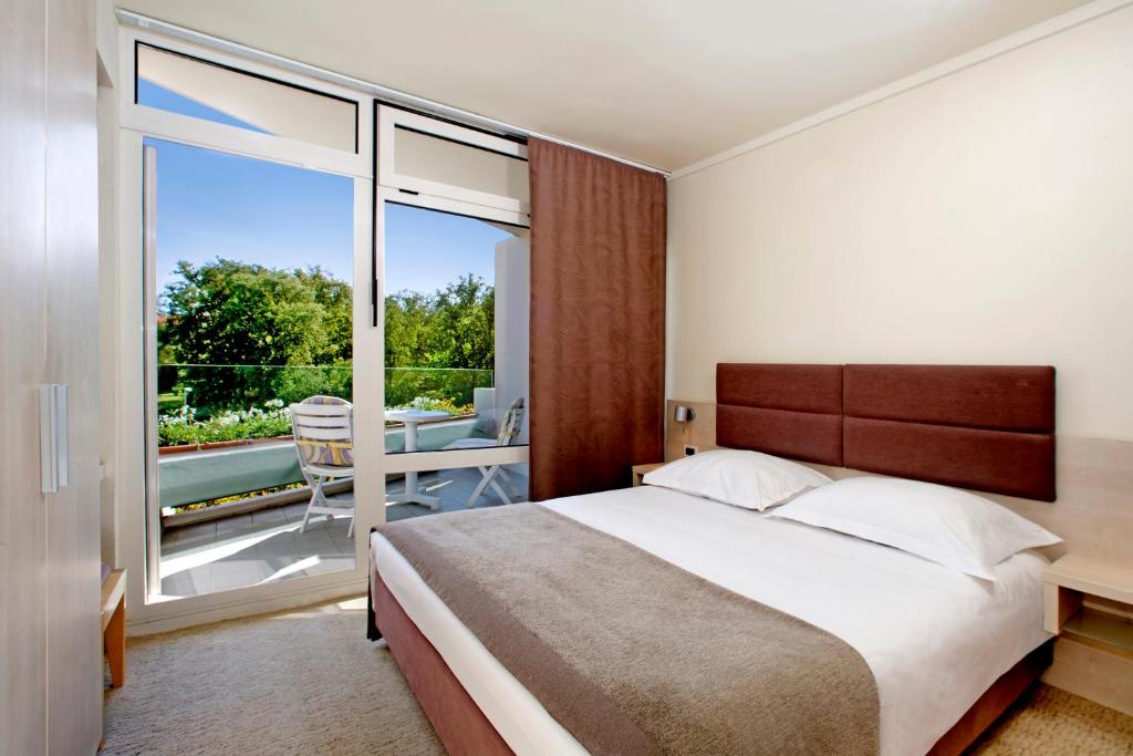 a bedroom with a large bed and a balcony at Hotel Mediteran Plava Laguna in Poreč