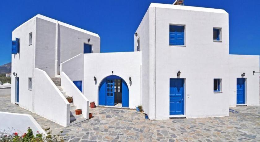 a white building with blue doors and stairs at Papikinou Studios in Adamas