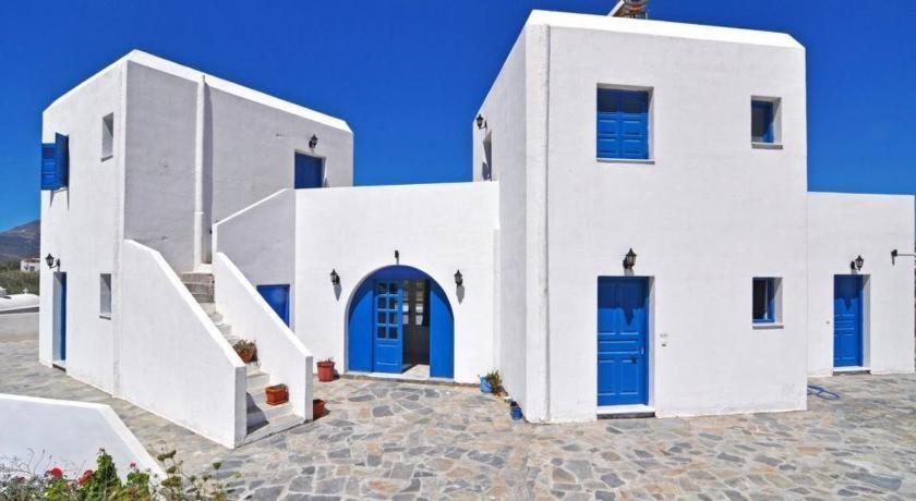 a white building with blue doors and stairs at Papikinou Studios in Adamantas