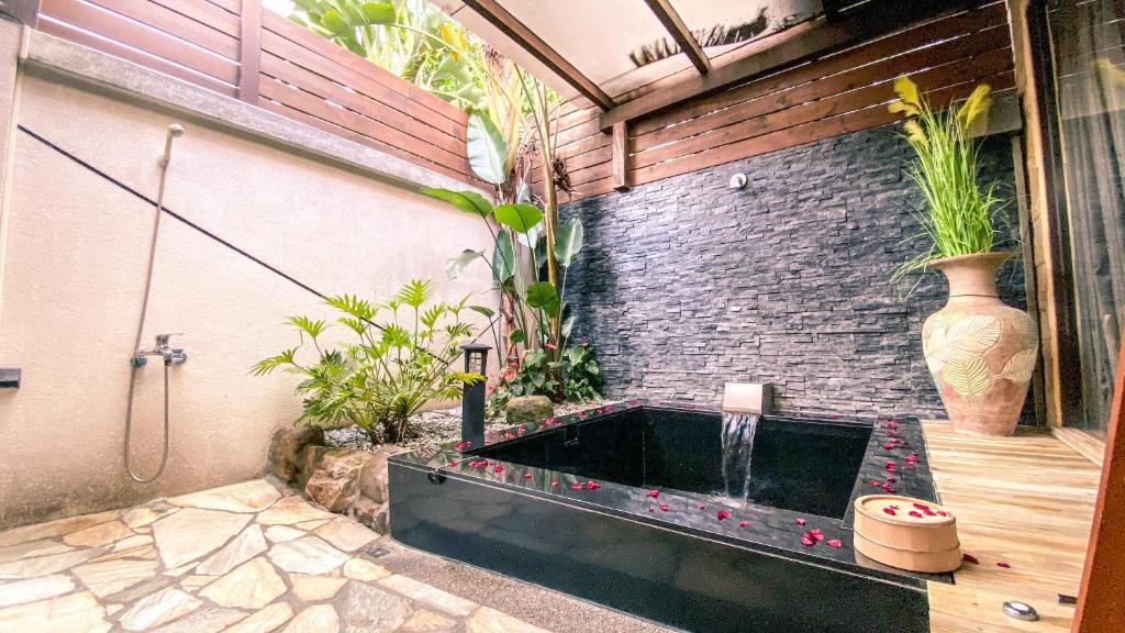 a bathroom with a bathtub with plants in it at Yage Hotspring House in Jiaoxi